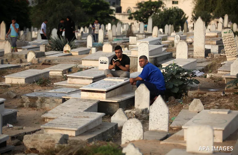 Palestinian men read the Koran next to the grave of their relative at a cemetery on the first day of Eid al-Fitr celebrations, which marks the end of the holy fasting month of Ramadan, in Gaza City July 6, 2016. Photo by...