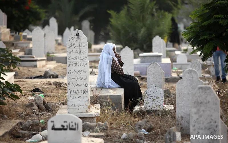 A Palestinian woman visits the grave of her relative at a cemetery on the first day of Eid al-Fitr celebrations, which marks the end of the holy fasting month of Ramadan, in Gaza City July 6, 2016. Photo by Ashraf Amra