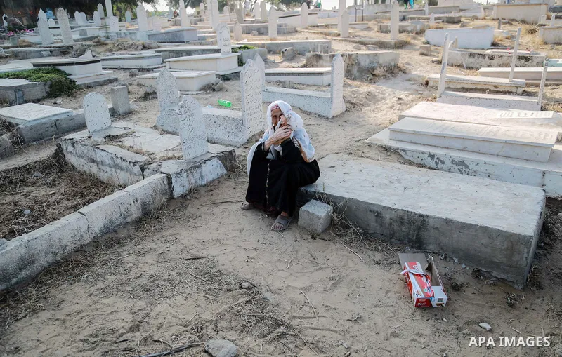 A Palestinian woman visits the grave of her relative at a cemetery on the first day of Eid al-Fitr celebrations, which marks the end of the holy fasting month of Ramadan, in Gaza City July 6, 2016. Photo by Mohammed Dahm...