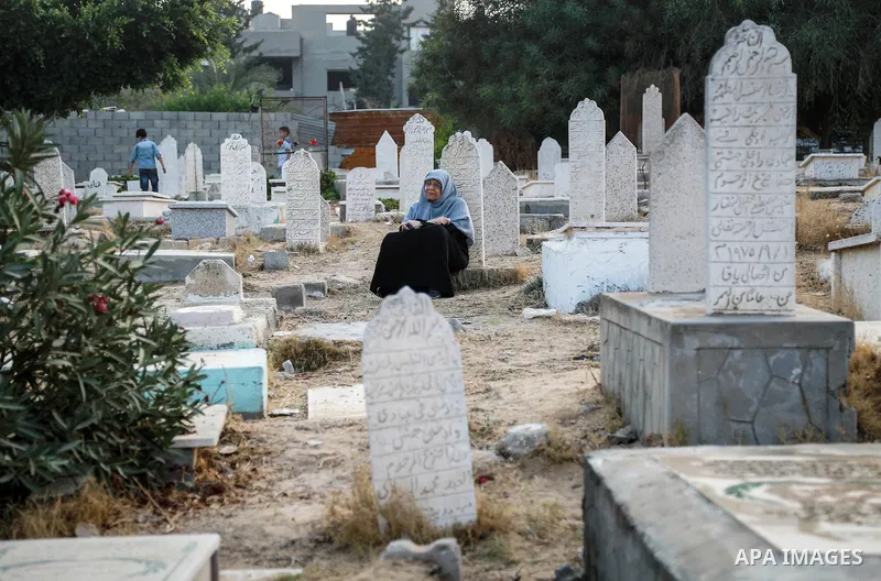 A Palestinian woman visits the grave of her relative at a cemetery on the first day of Eid al-Fitr celebrations, which marks the end of the holy fasting month of Ramadan, in Gaza City July 6, 2016. Photo by Mohammed Dahm...