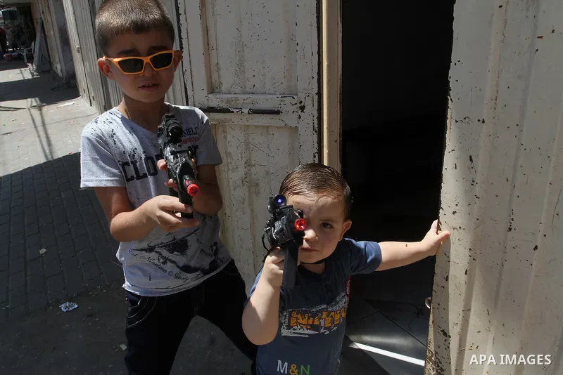 Palestinian boys play with toy guns to celebrate Eid al-Fitr during the second day of the holiday of Eid al-Fitr marking the end of Islam's fasting holy month of Ramadan, in Rafah in the southern Gaza strip, on July 7, 2...