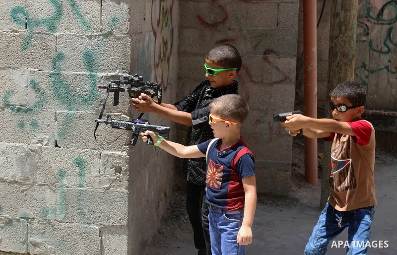 Palestinian boys play with toy guns to celebrate Eid al-Fitr during the second day of the holiday of Eid al-Fitr marking the end of Islam's fasting holy month of Ramadan, in Rafah in the southern Gaza strip, on July 7, 2...