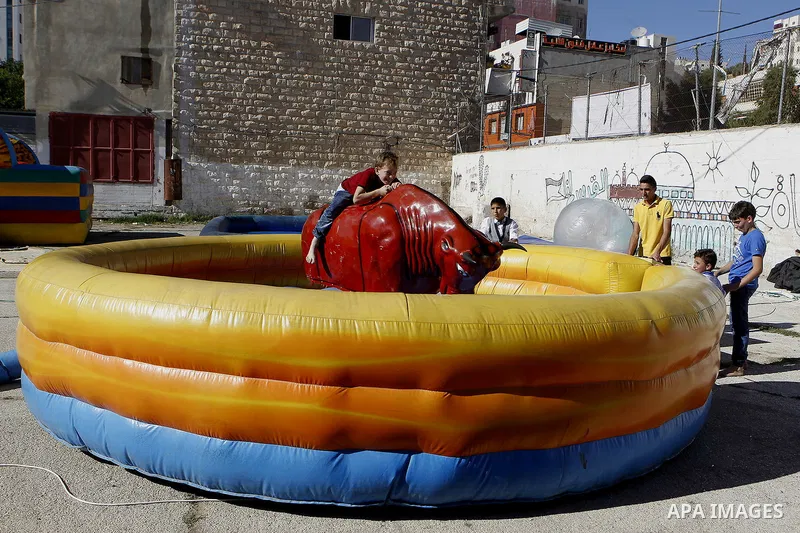 Palestinian children play to celebrate Eid al-Fitr during the second day of the holiday of Eid al-Fitr marking the end of Islam's fasting holy month of Ramadan, in the West Bank city of Hebron, on July 7, 2016. Photo by...