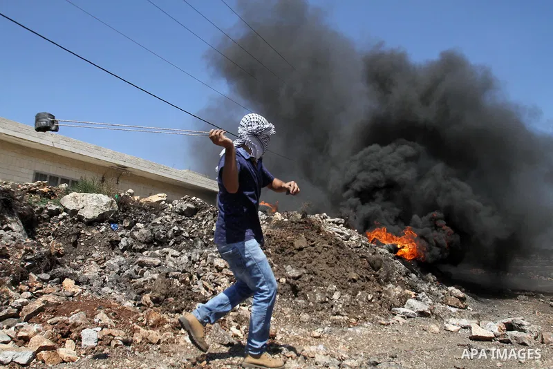 A Palestinian protester uses a slingshot to hurl stones towards Israeli security forces during clashes following a demonstration against the expropriation of Palestinian land by Israel on July 08, 2016 in the village of...