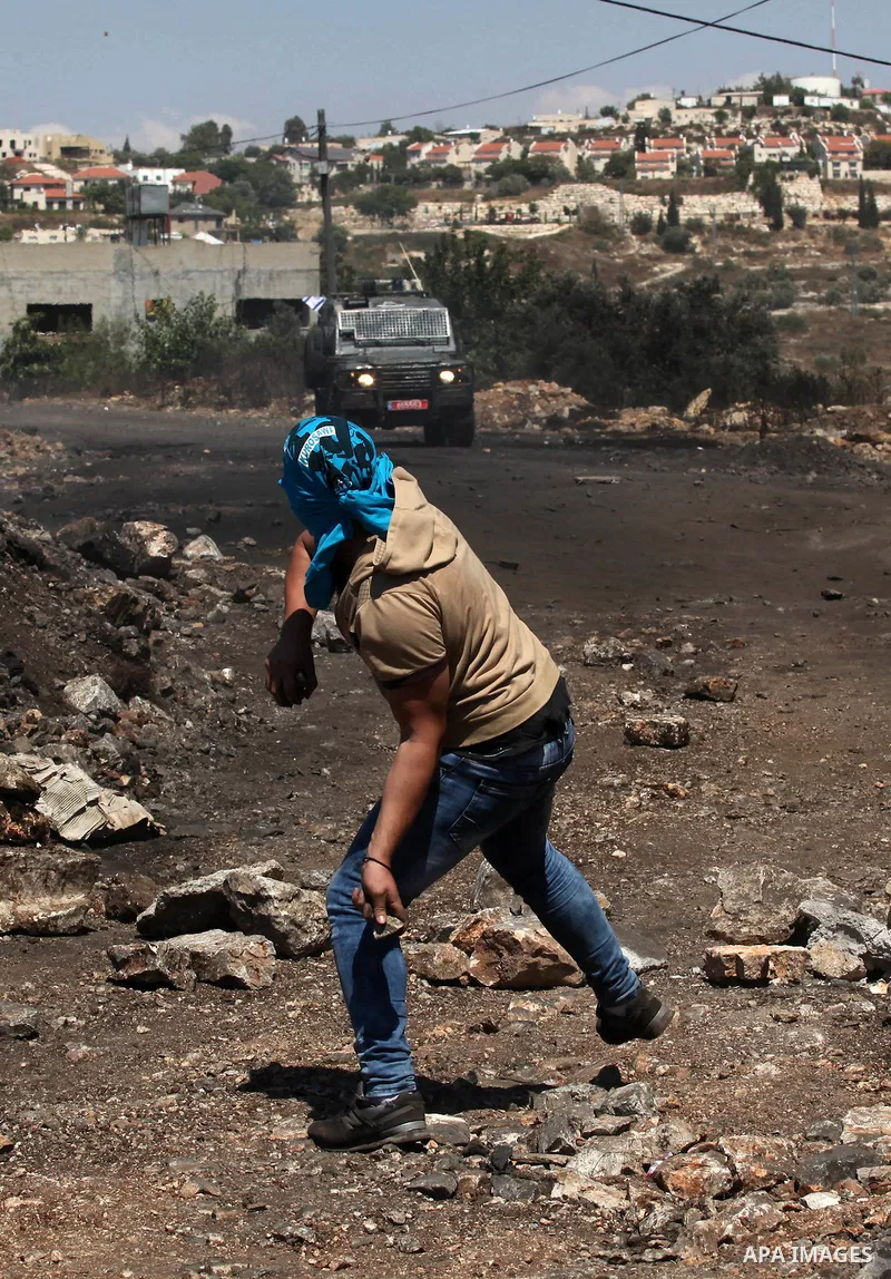 A Palestinian protester uses a slingshot to hurl stones towards Israeli security forces during clashes following a demonstration against the expropriation of Palestinian land by Israel on July 08, 2016 in the village of...