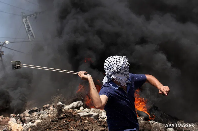 A Palestinian protester uses a slingshot to hurl stones towards Israeli security forces during clashes following a demonstration against the expropriation of Palestinian land by Israel on July 08, 2016 in the village of...