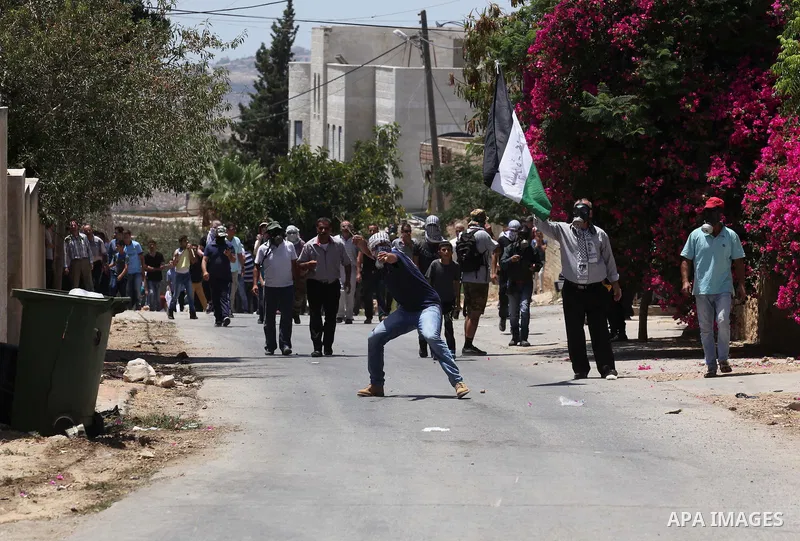 A Palestinian protester uses a slingshot to hurl stones towards Israeli security forces during clashes following a demonstration against the expropriation of Palestinian land by Israel on July 08, 2016 in the village of...