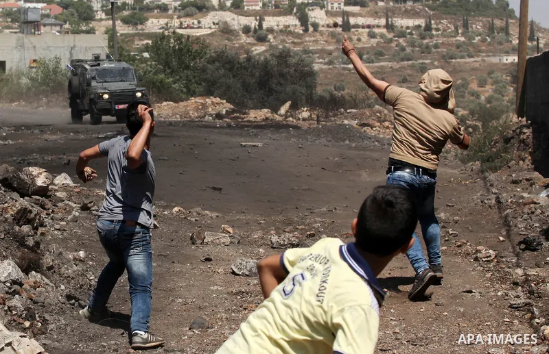 A Palestinian protester uses a slingshot to hurl stones towards Israeli security forces during clashes following a demonstration against the expropriation of Palestinian land by Israel on July 08, 2016 in the village of...
