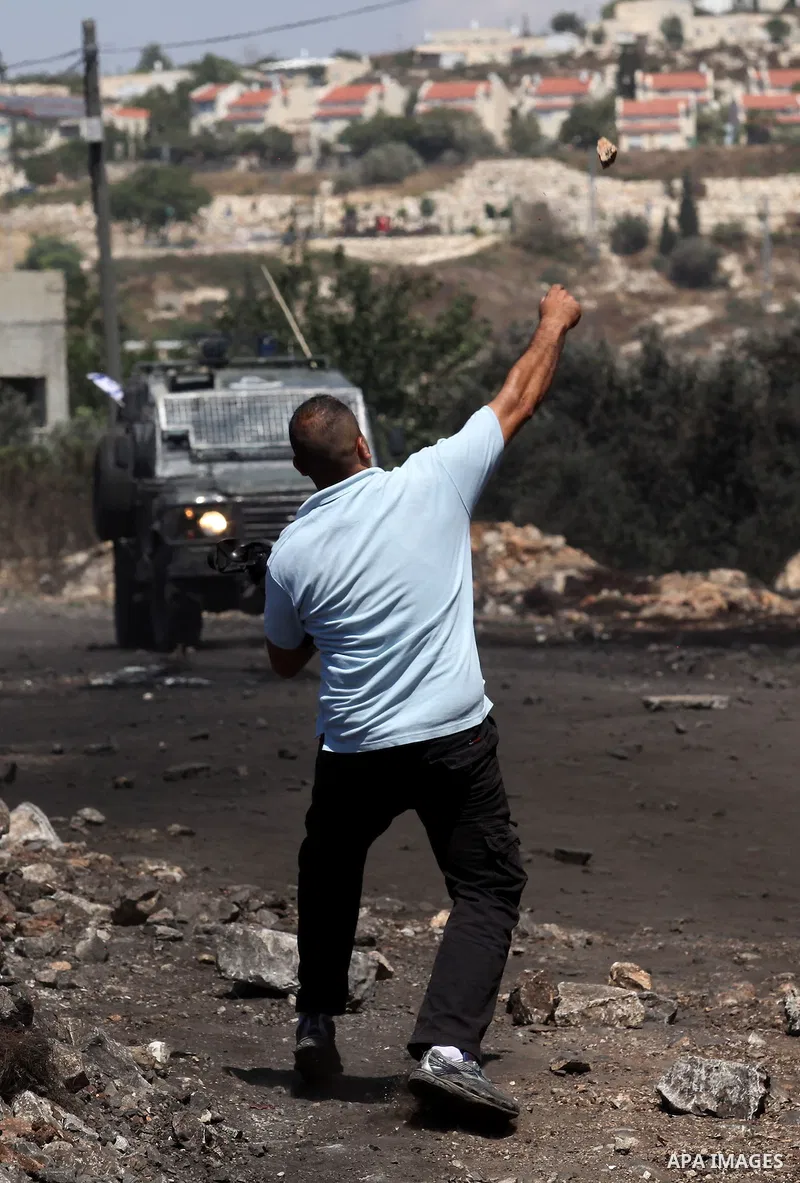 A Palestinian protester uses a slingshot to hurl stones towards Israeli security forces during clashes following a demonstration against the expropriation of Palestinian land by Israel on July 08, 2016 in the village of...