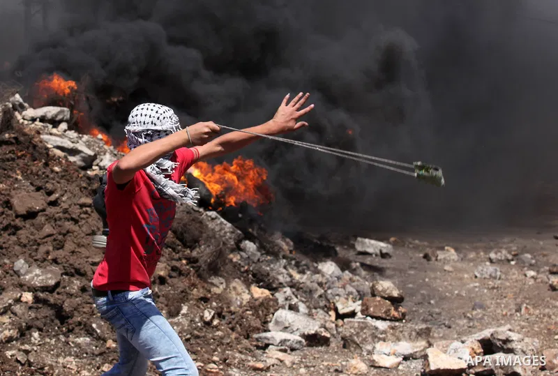 A Palestinian protester uses a slingshot to hurl stones towards Israeli security forces during clashes following a demonstration against the expropriation of Palestinian land by Israel on July 08, 2016 in the village of...