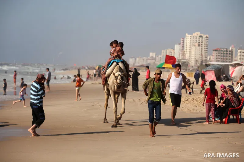 Palestinian children ride a camel at the beach of the Mediterranean sea on the coast of Gaza city, on the third day of Eid al-Fitr holiday which marks the end of the Muslim holy month of Ramadan, on July 08, 2016. Photo...