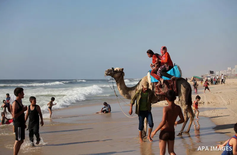 Palestinian children ride a camel at the beach of the Mediterranean sea on the coast of Gaza city, on the third day of Eid al-Fitr holiday which marks the end of the Muslim holy month of Ramadan, on July 08, 2016. Photo...