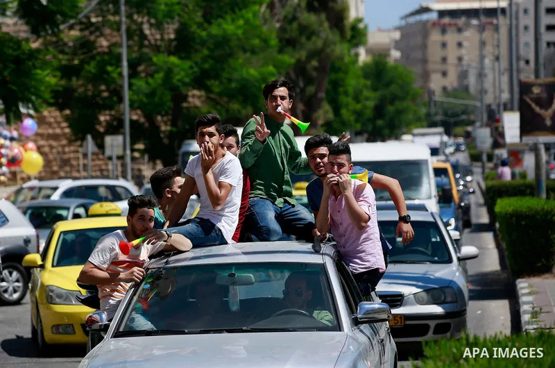 Palestinian high school students celebrate after heard their results of final exams known as "Tawjihi", in the West Bank city of Hebron on July 11, 2016. Photo by Wisam Hashlamoun