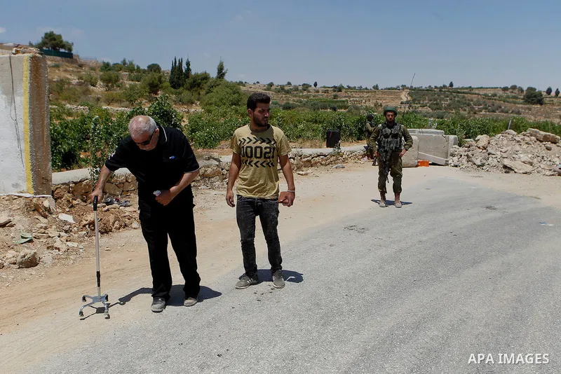 Palestinian men get round a roadblock, on July 11, 2016 in the West Bank village of Sair, east of Hebron, as the army keeps the area under lockdown afer an Israeli man was shot and wounded while driving his car near the...