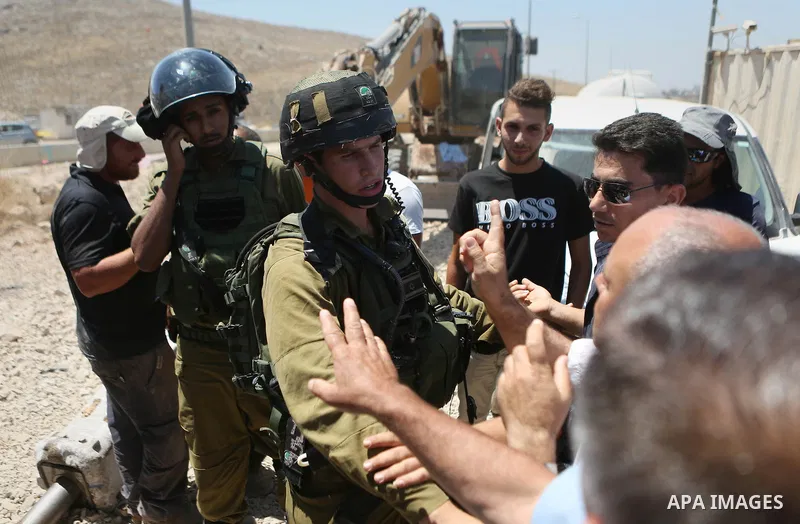 A Palestinian man argues with an Israeli soldier as he tries to prevent an Israeli excavator from clearing his land during a protest against Jewish settlements, near the village of Deir Qaddis near the West Bank city of...