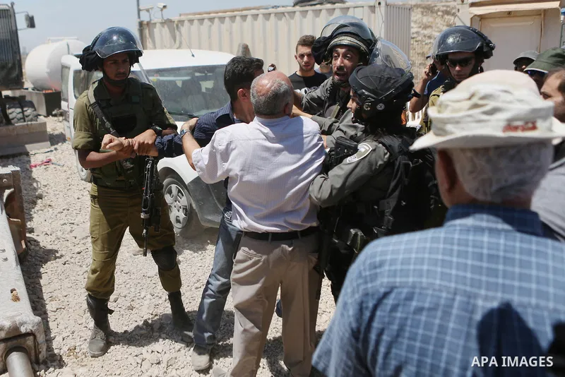 A Palestinian man argues with an Israeli soldier as he tries to prevent an Israeli excavator from clearing his land during a protest against Jewish settlements, near the village of Deir Qaddis near the West Bank city of...