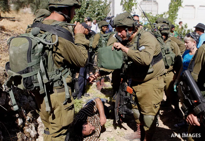 Israeli army soldiers detain a Palestinian as peace activists clean around Palestinian houses in Tal Rumaida in the West Bank city of Hebron July 15, 2016. Photo by Wisam Hashlamoun