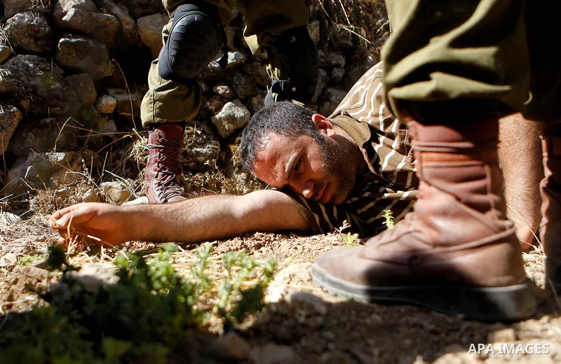 Israeli army soldiers detain a Palestinian as peace activists clean around Palestinian houses in Tal Rumaida in the West Bank city of Hebron July 15, 2016. Photo by Wisam Hashlamoun