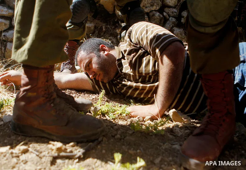 Israeli army soldiers detain a Palestinian as peace activists clean around Palestinian houses in Tal Rumaida in the West Bank city of Hebron July 15, 2016. Photo by Wisam Hashlamoun