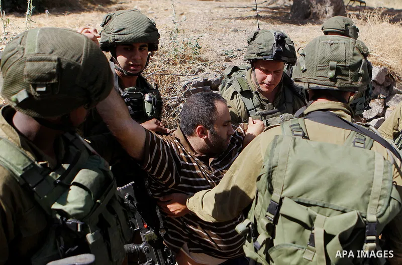 Israeli army soldiers detain a Palestinian as peace activists clean around Palestinian houses in Tal Rumaida in the West Bank city of Hebron July 15, 2016. Photo by Wisam Hashlamoun