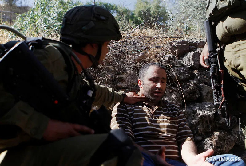 Israeli army soldiers detain a Palestinian as peace activists clean around Palestinian houses in Tal Rumaida in the West Bank city of Hebron July 15, 2016. Photo by Wisam Hashlamoun