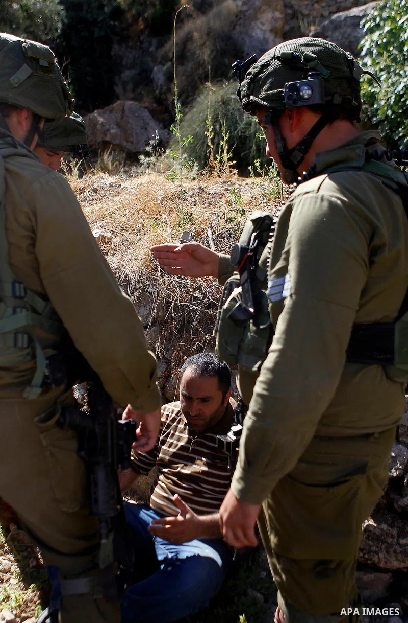 Israeli army soldiers detain a Palestinian as peace activists clean around Palestinian houses in Tal Rumaida in the West Bank city of Hebron July 15, 2016. Photo by Wisam Hashlamoun