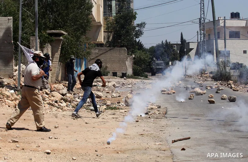 Palestinian protesters run for cover from a tear gas canister fired by Israeli security forces during clashes following a demonstration against the expropriation of Palestinian land by Israel on July 15, 2016 in the vill...