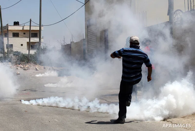 A Palestinian protester kicks back a tear gas canister fired by Israeli security forces during clashes following a demonstration against the expropriation of Palestinian land by Israel on July 15, 2016 in the village of...
