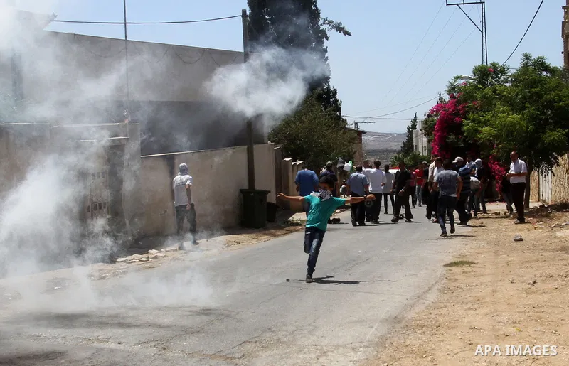 A Palestinian protester kicks back a tear gas canister fired by Israeli security forces during clashes following a demonstration against the expropriation of Palestinian land by Israel on July 15, 2016 in the village of...
