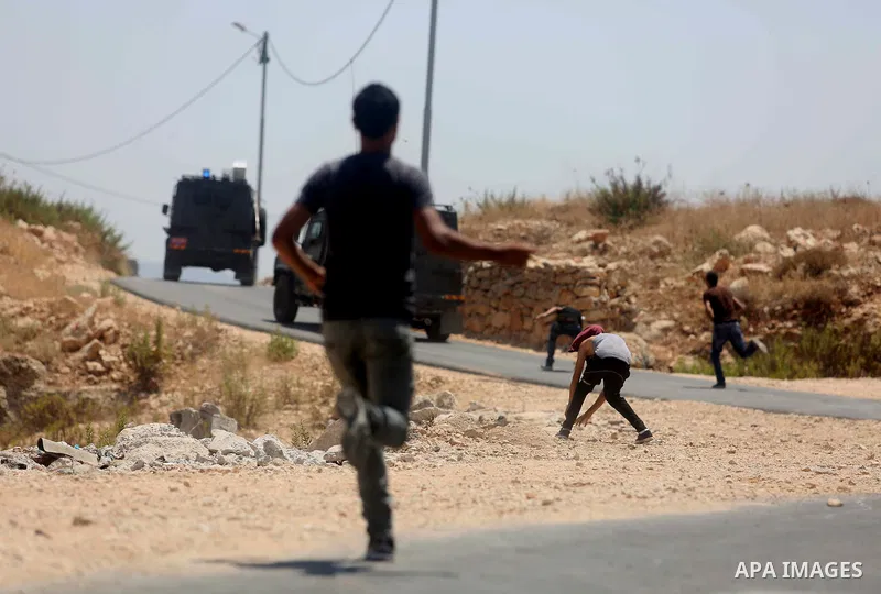 Palestinian Protesters hurl stones toward Israeli security forces during clashes following a demonstration against Israel's controversial separation barrier and Jewish settlements, in the West Bank village of Bilin, near...