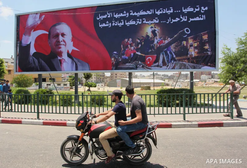 Palestinians walk past a billboard bearing a portrait of Turkish President Recep Tayyip Erdogan in Gaza City, on July 17, 2016. The writing in Arabic reads: "Supporting Turkey...its wise leadership and its inherent peopl...