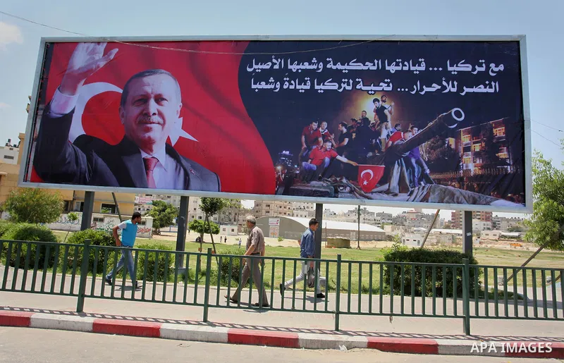 Palestinians walk past a billboard bearing a portrait of Turkish President Recep Tayyip Erdogan in Gaza City, on July 17, 2016. The writing in Arabic reads: "Supporting Turkey...its wise leadership and its inherent peopl...