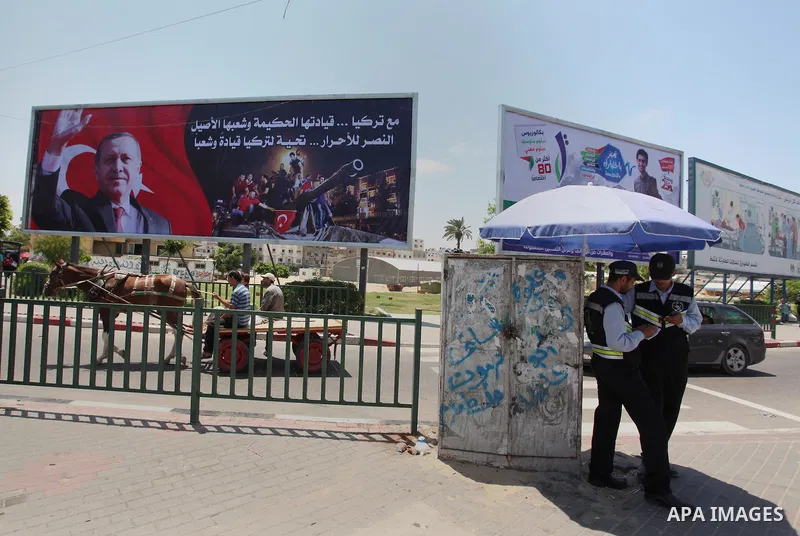 Palestinians walk past a billboard bearing a portrait of Turkish President Recep Tayyip Erdogan in Gaza City, on July 17, 2016. The writing in Arabic reads: "Supporting Turkey...its wise leadership and its inherent peopl...