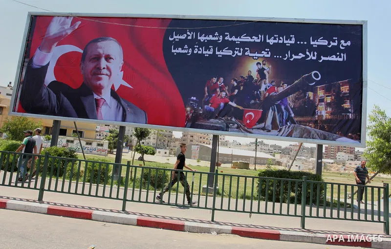 Palestinians walk past a billboard bearing a portrait of Turkish President Recep Tayyip Erdogan in Gaza City, on July 17, 2016. The writing in Arabic reads: "Supporting Turkey...its wise leadership and its inherent peopl...