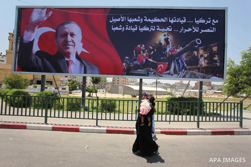 Palestinians walk past a billboard bearing a portrait of Turkish President Recep Tayyip Erdogan in Gaza City, on July 17, 2016. The writing in Arabic reads: "Supporting Turkey...its wise leadership and its inherent peopl...