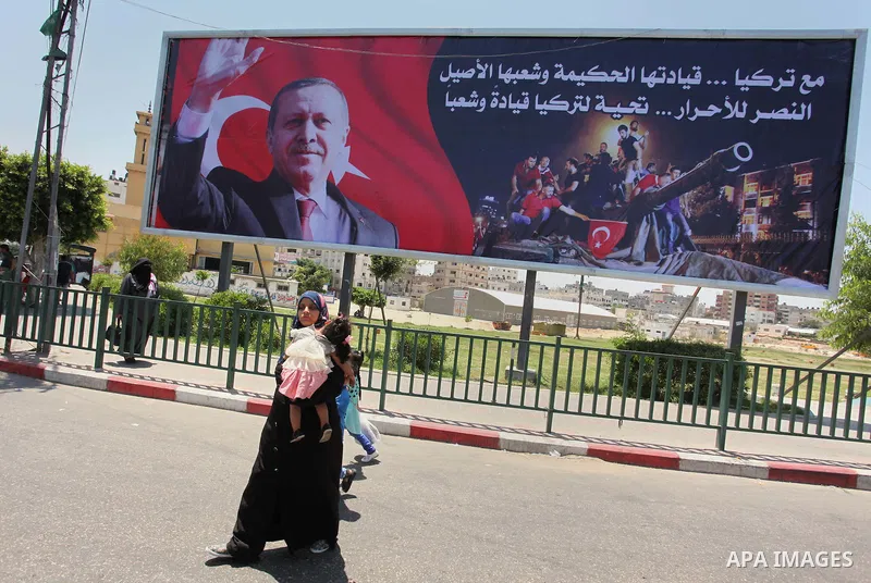 Palestinians walk past a billboard bearing a portrait of Turkish President Recep Tayyip Erdogan in Gaza City, on July 17, 2016. The writing in Arabic reads: "Supporting Turkey...its wise leadership and its inherent peopl...