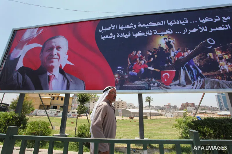 Palestinians walk past a billboard bearing a portrait of Turkish President Recep Tayyip Erdogan in Gaza City, on July 17, 2016. The writing in Arabic reads: "Supporting Turkey...its wise leadership and its inherent peopl...