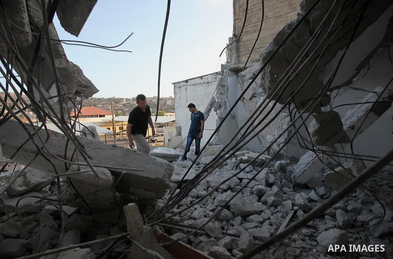 Palestinian men check on July 18, 2016 the rubble of a house belonging to a Palestinian man accused by Israeli authorities in taking part in an attack in Jerusalem in which an Israeli policewoman was killed, after it was...