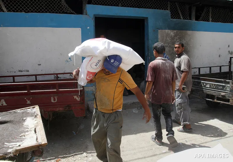Palestinians receive Turkish aid at an aid distribution centre of the United Nations Relief and Works Agency (UNRWA) in the southern Gaza Strip town of Rafah, on July 18, 2016. Photo by Abed Rahim Khatib