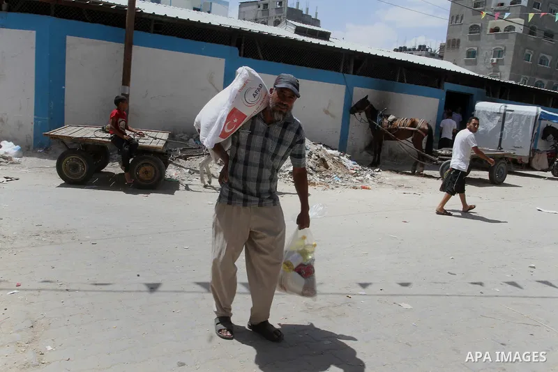 Palestinians receive Turkish aid at an aid distribution centre of the United Nations Relief and Works Agency (UNRWA) in the southern Gaza Strip town of Rafah, on July 18, 2016. Photo by Abed Rahim Khatib