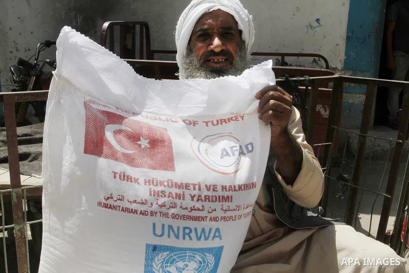 Palestinians receive Turkish aid at an aid distribution centre of the United Nations Relief and Works Agency (UNRWA) in the southern Gaza Strip town of Rafah, on July 18, 2016. Photo by Abed Rahim Khatib