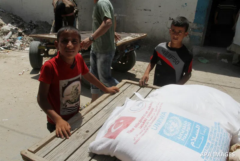 Palestinians receive Turkish aid at an aid distribution centre of the United Nations Relief and Works Agency (UNRWA) in the southern Gaza Strip town of Rafah, on July 18, 2016. Photo by Abed Rahim Khatib