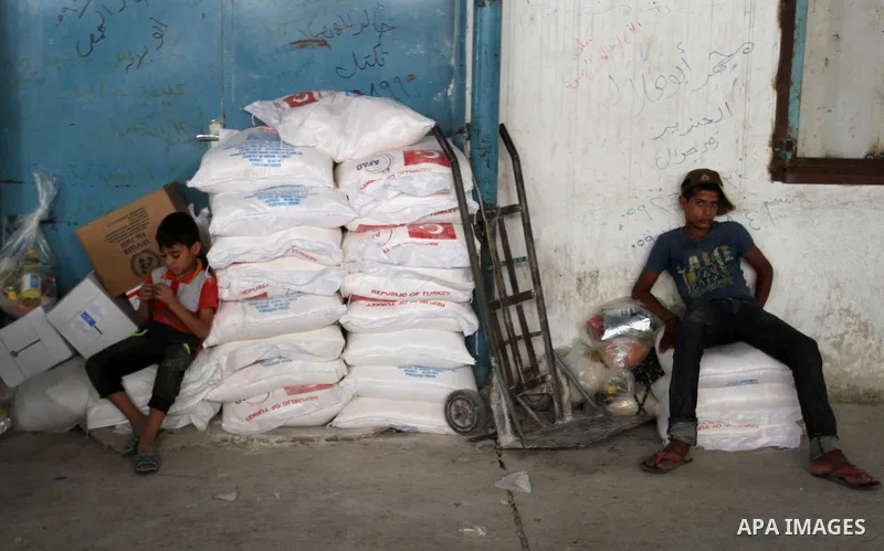 Palestinians receive Turkish aid at an aid distribution centre of the United Nations Relief and Works Agency (UNRWA) in the southern Gaza Strip town of Rafah, on July 18, 2016. Photo by Abed Rahim Khatib