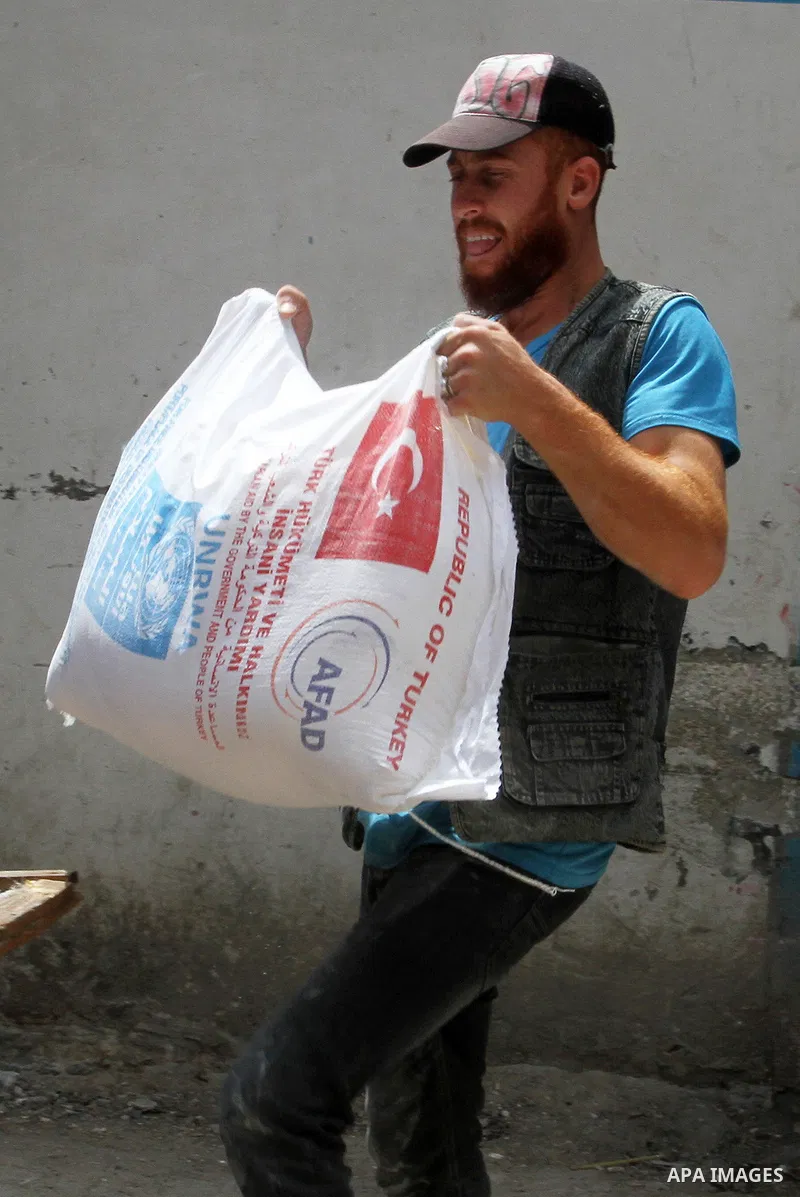 Palestinians receive Turkish aid at an aid distribution centre of the United Nations Relief and Works Agency (UNRWA) in the southern Gaza Strip town of Rafah, on July 18, 2016. Photo by Abed Rahim Khatib