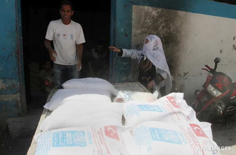 Palestinians receive Turkish aid at an aid distribution centre of the United Nations Relief and Works Agency (UNRWA) in the southern Gaza Strip town of Rafah, on July 18, 2016. Photo by Abed Rahim Khatib