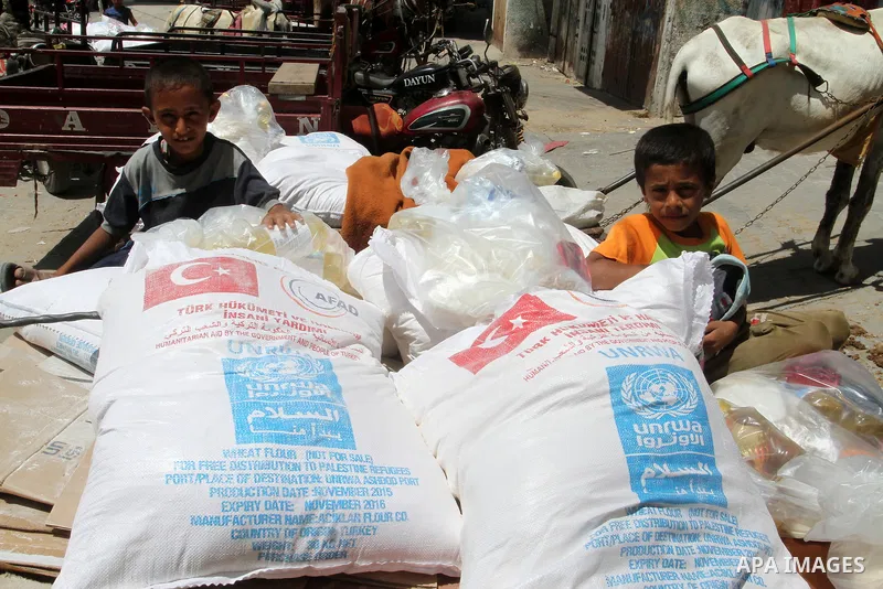 Palestinians receive Turkish aid at an aid distribution centre of the United Nations Relief and Works Agency (UNRWA) in the southern Gaza Strip town of Rafah, on July 18, 2016. Photo by Abed Rahim Khatib