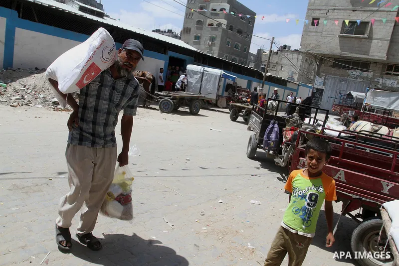 Palestinians receive Turkish aid at an aid distribution centre of the United Nations Relief and Works Agency (UNRWA) in the southern Gaza Strip town of Rafah, on July 18, 2016. Photo by Abed Rahim Khatib