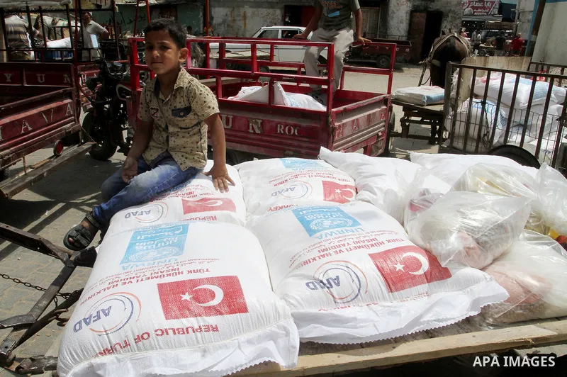 Palestinians receive Turkish aid at an aid distribution centre of the United Nations Relief and Works Agency (UNRWA) in the southern Gaza Strip town of Rafah, on July 18, 2016. Photo by Abed Rahim Khatib