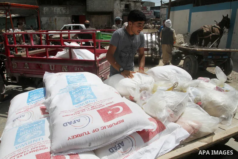 Palestinians receive Turkish aid at an aid distribution centre of the United Nations Relief and Works Agency (UNRWA) in the southern Gaza Strip town of Rafah, on July 18, 2016. Photo by Abed Rahim Khatib