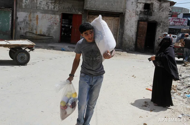 Palestinians receive Turkish aid at an aid distribution centre of the United Nations Relief and Works Agency (UNRWA) in the southern Gaza Strip town of Rafah, on July 18, 2016. Photo by Abed Rahim Khatib